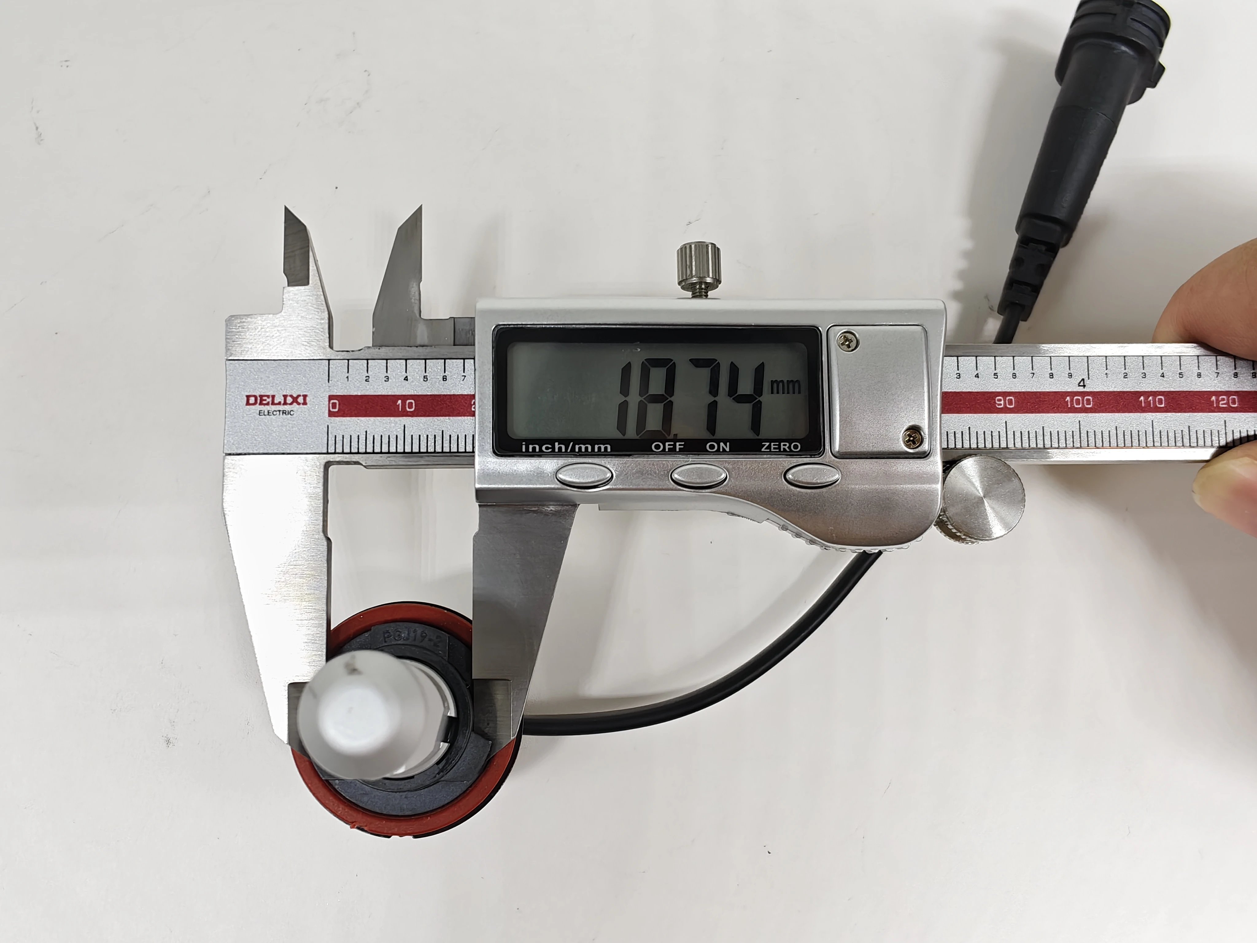 Outer-diameter measurement of the Philips H11 LEDr base locating section with the digital caliper reading oriented for normal reading